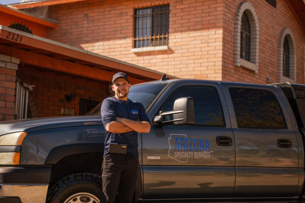 An exterminator in Tucson standing in front of a grey truck